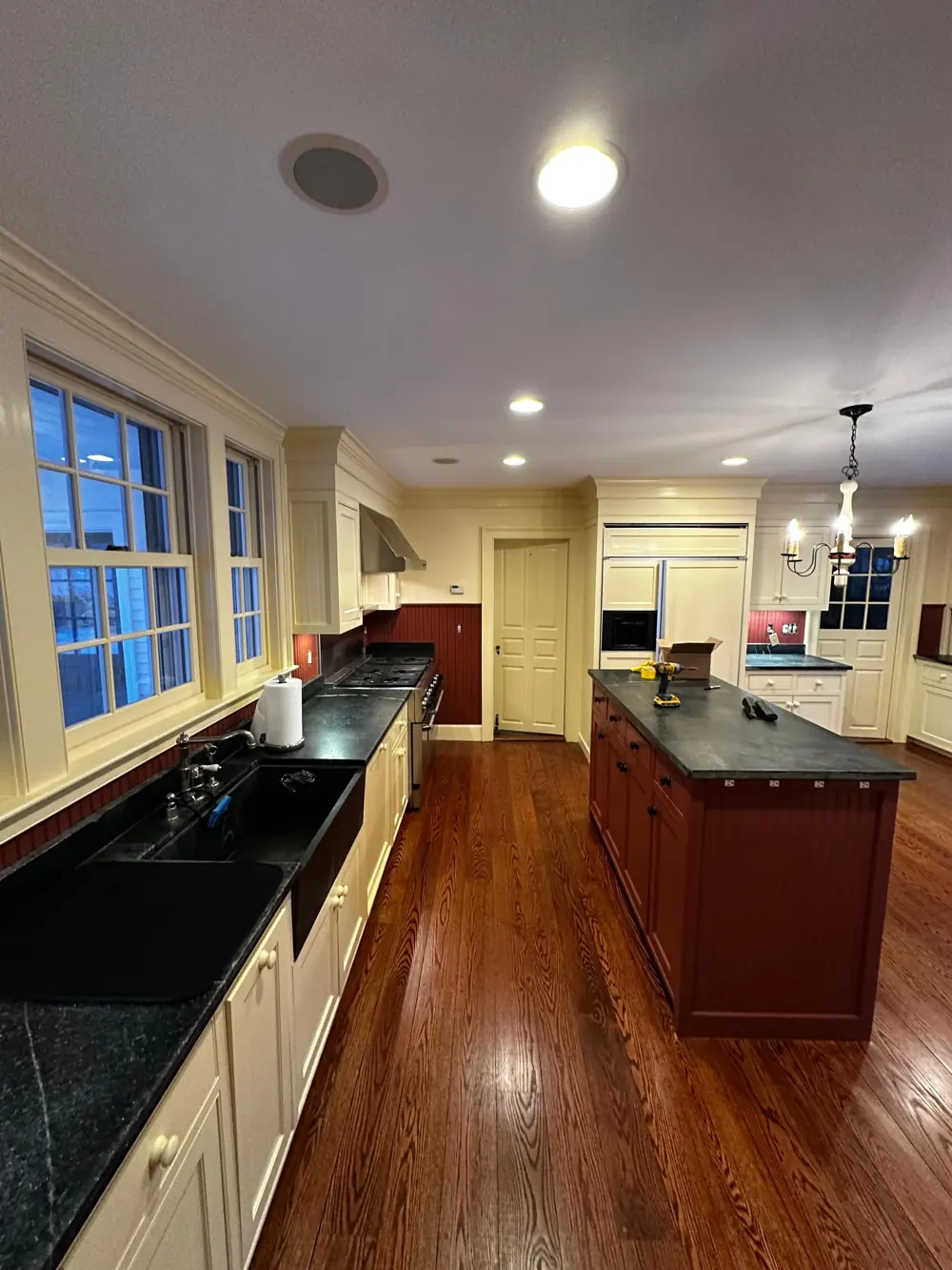 Kitchen with cream cabinetry, red island and hardwood floor